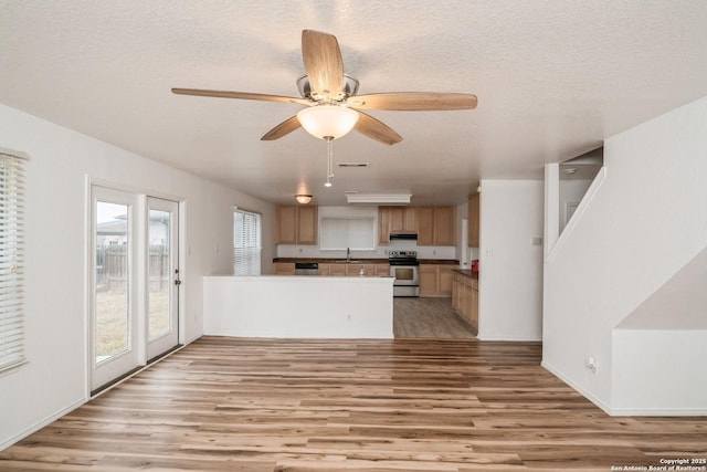 kitchen featuring stainless steel appliances, light wood finished floors, a peninsula, and a sink