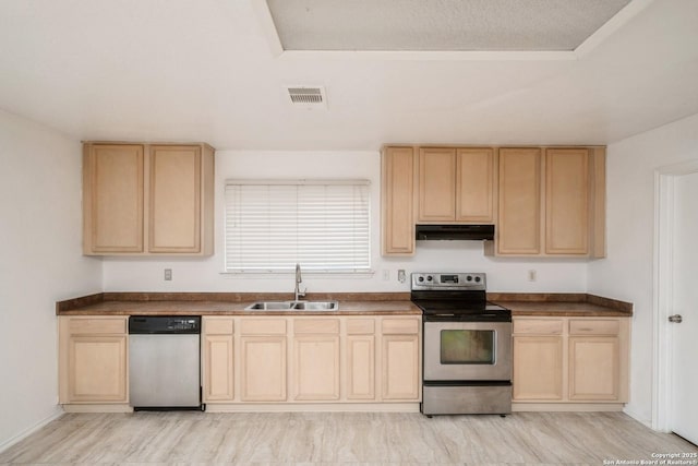 kitchen with visible vents, appliances with stainless steel finishes, light brown cabinets, a sink, and under cabinet range hood