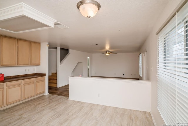 kitchen with dark countertops, ceiling fan, a textured ceiling, and light brown cabinetry