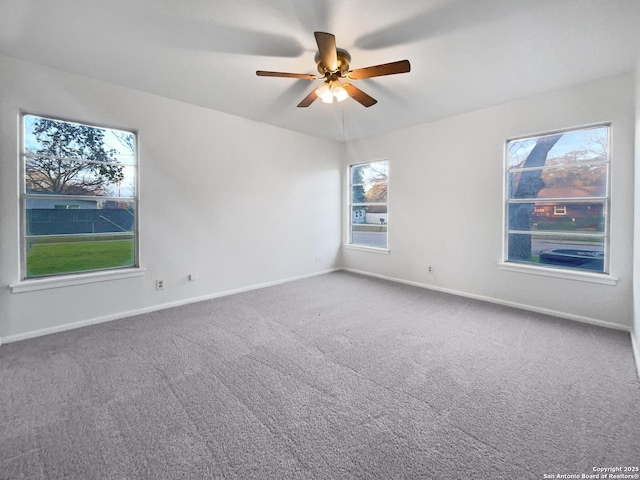 carpeted empty room with a ceiling fan and baseboards