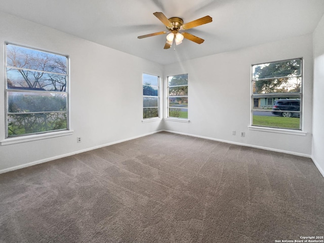 empty room featuring dark carpet, baseboards, and ceiling fan