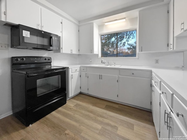 kitchen featuring light countertops, light wood-style floors, white cabinets, a sink, and black appliances