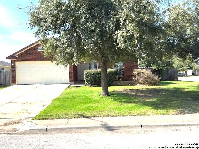 obstructed view of property with a garage, concrete driveway, a front lawn, and brick siding