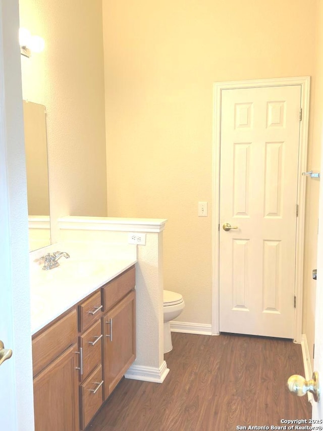 bathroom with toilet, baseboards, wood finished floors, and vanity