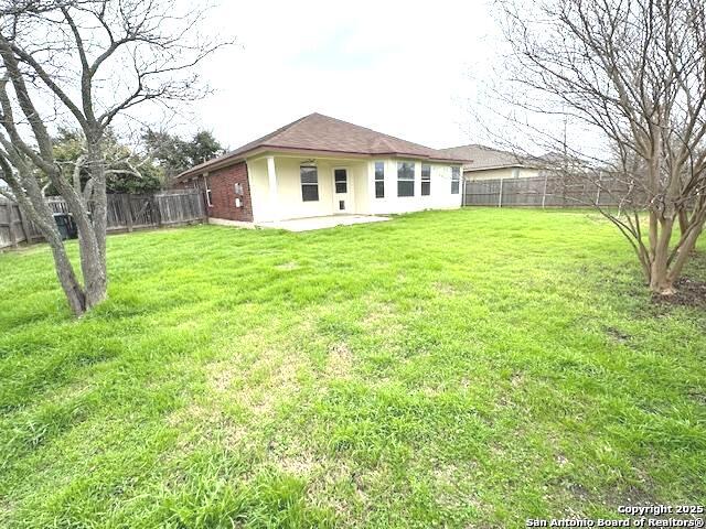 rear view of house featuring a patio, a lawn, and a fenced backyard