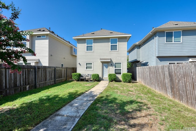 rear view of property with a yard and a fenced backyard