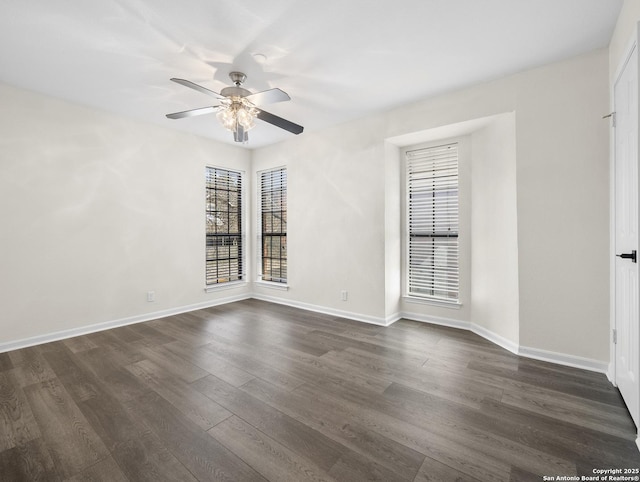 empty room with ceiling fan, dark wood finished floors, and baseboards