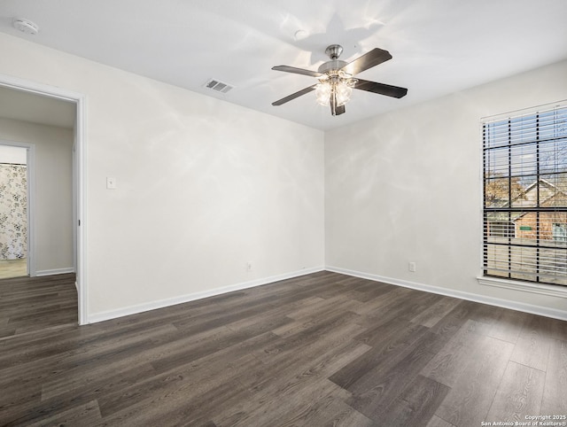 spare room with dark wood-style floors, ceiling fan, visible vents, and baseboards