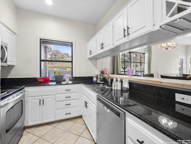 kitchen featuring light tile patterned floors, an inviting chandelier, appliances with stainless steel finishes, white cabinets, and a sink