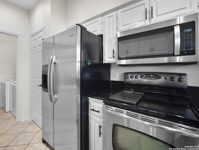 kitchen with light tile patterned floors, appliances with stainless steel finishes, independent washer and dryer, and white cabinetry