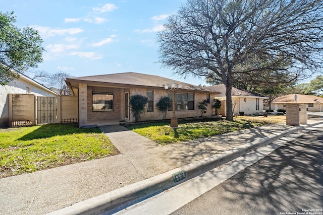 ranch-style home with brick siding, a front lawn, fence, and a gate