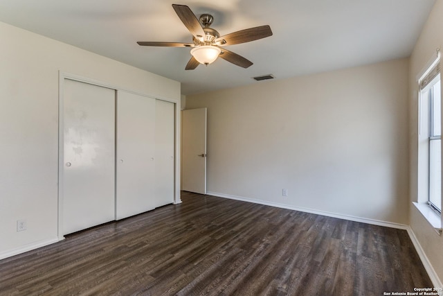 unfurnished bedroom featuring a ceiling fan, visible vents, baseboards, a closet, and dark wood-style floors