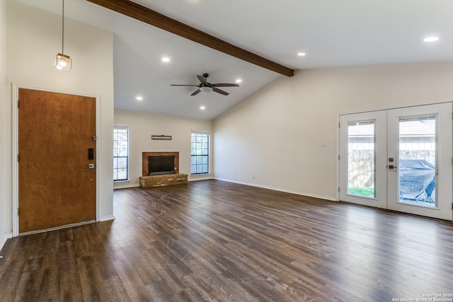 unfurnished living room featuring lofted ceiling with beams, a brick fireplace, dark wood-type flooring, and french doors