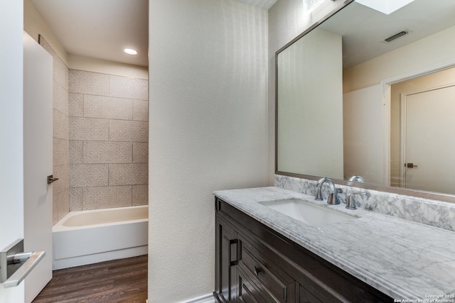 full bath with visible vents, a textured wall, vanity, and wood finished floors