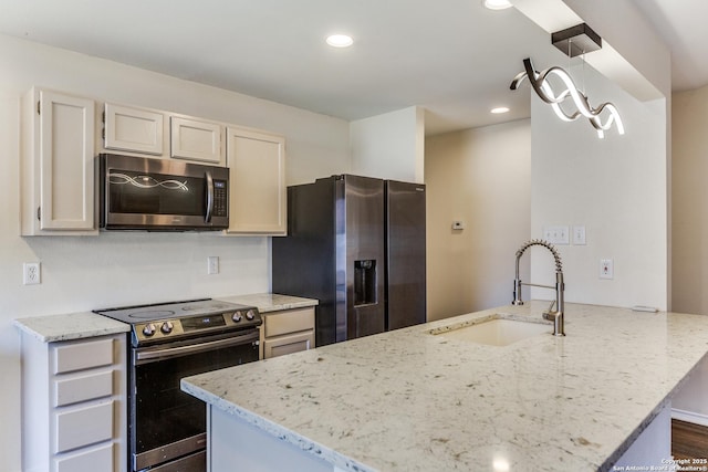 kitchen with light stone counters, a peninsula, stainless steel appliances, a sink, and recessed lighting