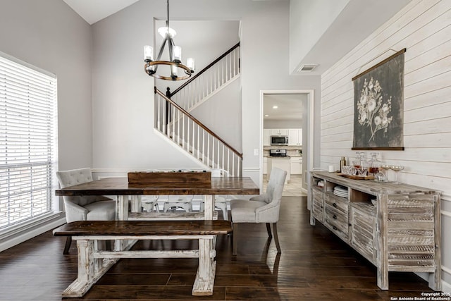 dining space with stairs, dark wood-style flooring, visible vents, and a notable chandelier