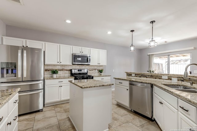 kitchen featuring stainless steel appliances, white cabinetry, a sink, and a kitchen island