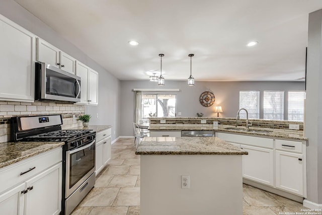 kitchen featuring a center island, tasteful backsplash, appliances with stainless steel finishes, white cabinets, and a sink