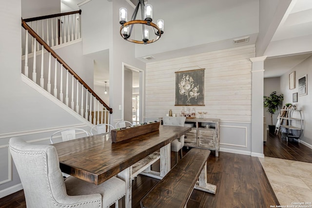 dining room featuring dark wood-style flooring, visible vents, a notable chandelier, and stairs