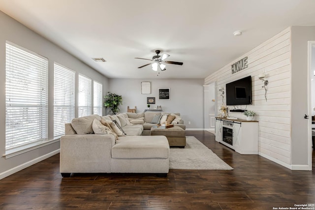 living room featuring visible vents, baseboards, dark wood-style floors, ceiling fan, and a fireplace