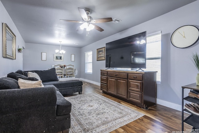 living room with visible vents, baseboards, dark wood-style flooring, and ceiling fan with notable chandelier