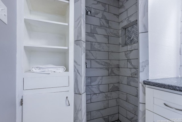 full bathroom featuring a tile shower and vanity