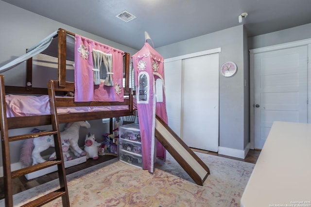 bedroom with light wood-style floors, visible vents, and a closet