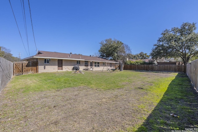 rear view of house with a yard, a fenced backyard, and brick siding