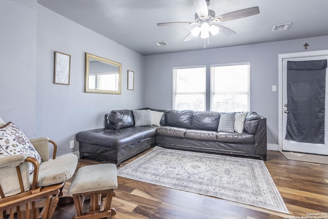 living area with baseboards, dark wood-style flooring, visible vents, and a ceiling fan