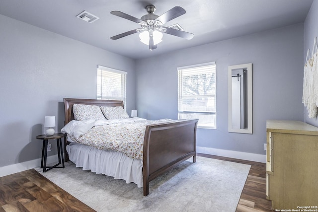 bedroom featuring dark wood-style floors, multiple windows, visible vents, and baseboards