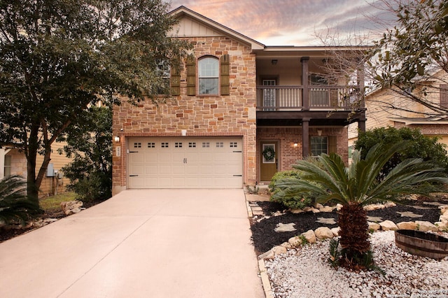 view of front of property with brick siding, concrete driveway, a balcony, a garage, and stone siding