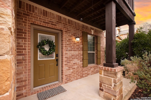 view of exterior entry with covered porch and brick siding