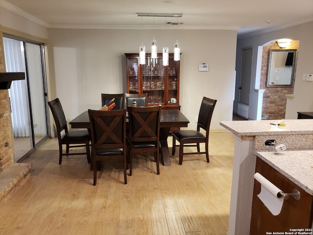 dining space with ornamental molding and light wood finished floors