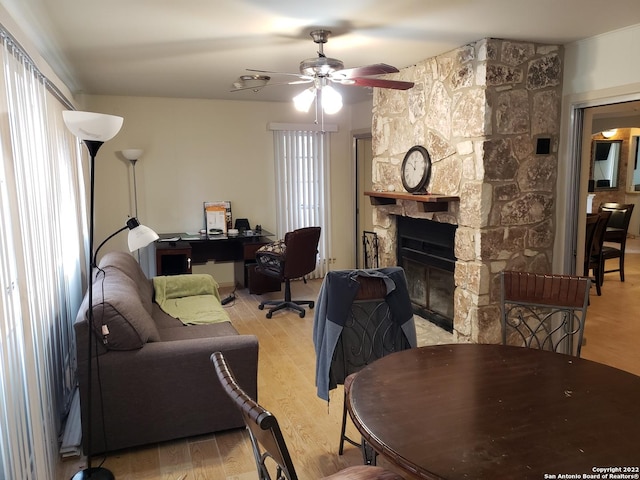 interior space with light wood finished floors, a ceiling fan, and a stone fireplace