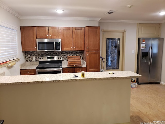 kitchen with stainless steel appliances, visible vents, light wood-style floors, ornamental molding, and brown cabinetry