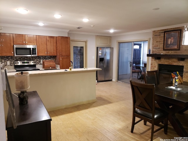 kitchen with a fireplace, light countertops, ornamental molding, appliances with stainless steel finishes, and brown cabinetry