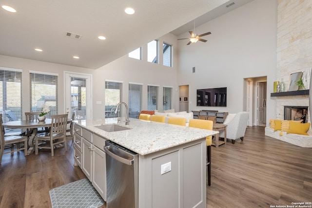 kitchen with dishwasher, open floor plan, a kitchen island with sink, a kitchen bar, and a sink