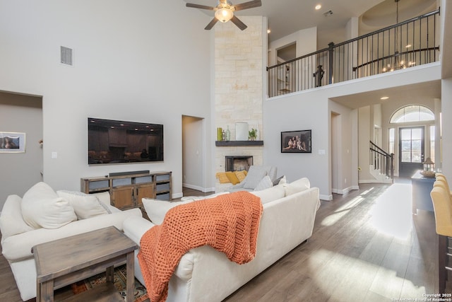 living room with a ceiling fan, visible vents, a fireplace, and wood finished floors