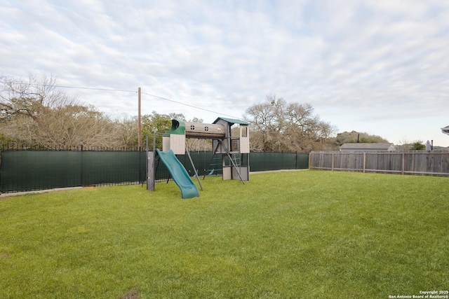 community play area with a fenced backyard and a yard