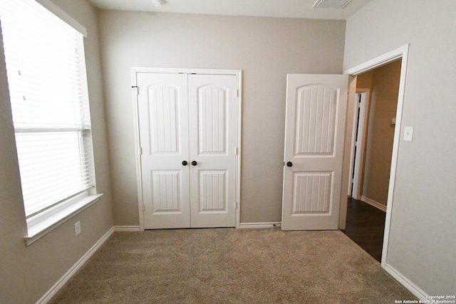 unfurnished bedroom featuring baseboards, visible vents, dark carpet, and a closet