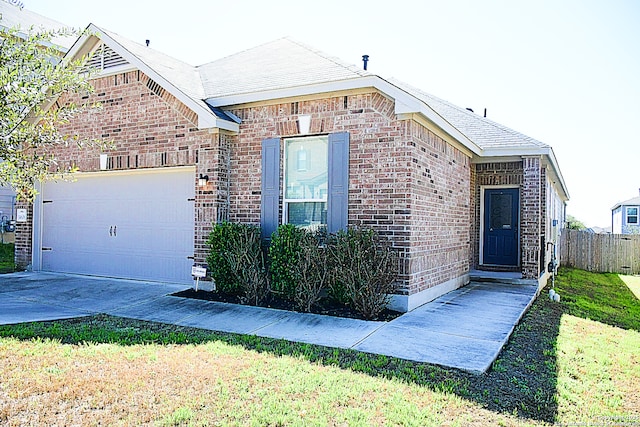 view of front facade featuring an attached garage, brick siding, fence, driveway, and a front yard