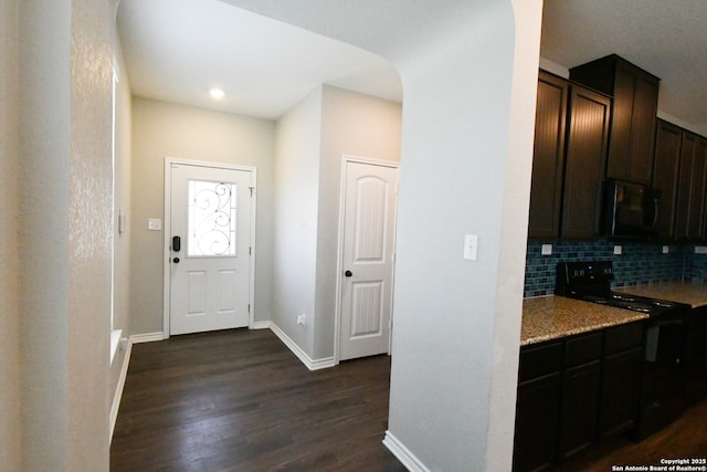 entryway featuring arched walkways, dark wood-style flooring, and baseboards