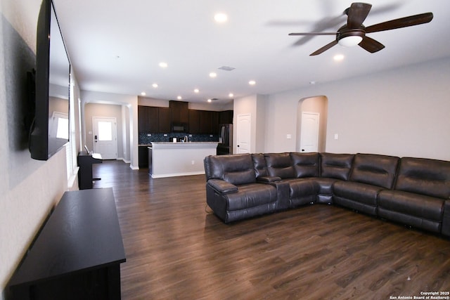 living room featuring arched walkways, dark wood-style flooring, recessed lighting, visible vents, and a ceiling fan