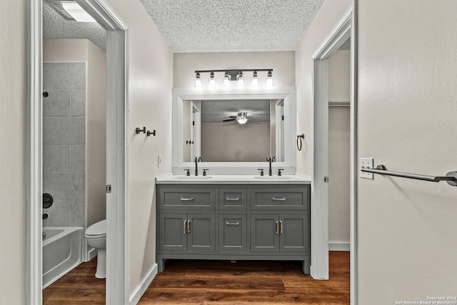 full bathroom with double vanity, a textured ceiling, a sink, and wood finished floors