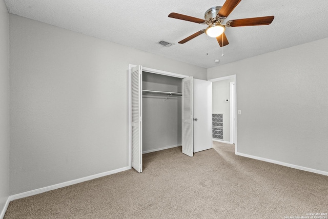 unfurnished bedroom featuring a textured ceiling, light colored carpet, visible vents, baseboards, and a closet