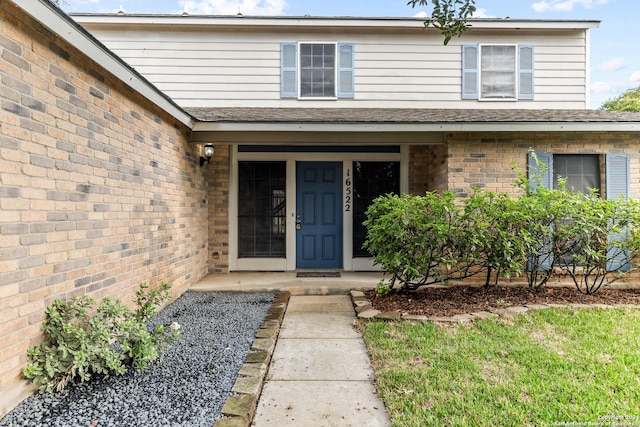 view of exterior entry featuring brick siding