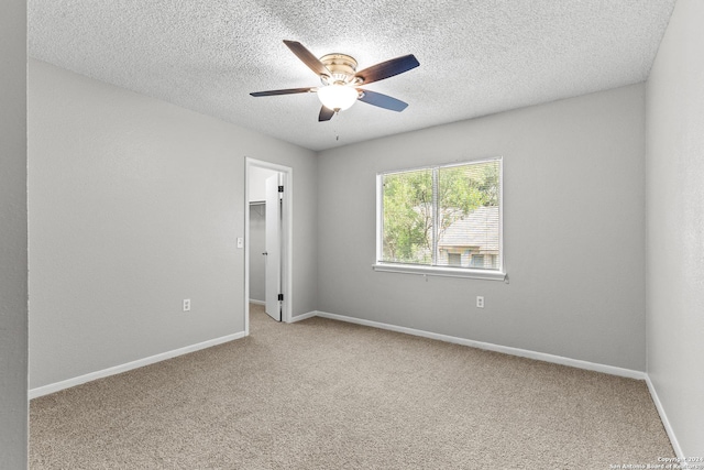 spare room with light carpet, ceiling fan, baseboards, and a textured ceiling