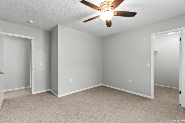 unfurnished bedroom with baseboards, a walk in closet, a closet, and light colored carpet