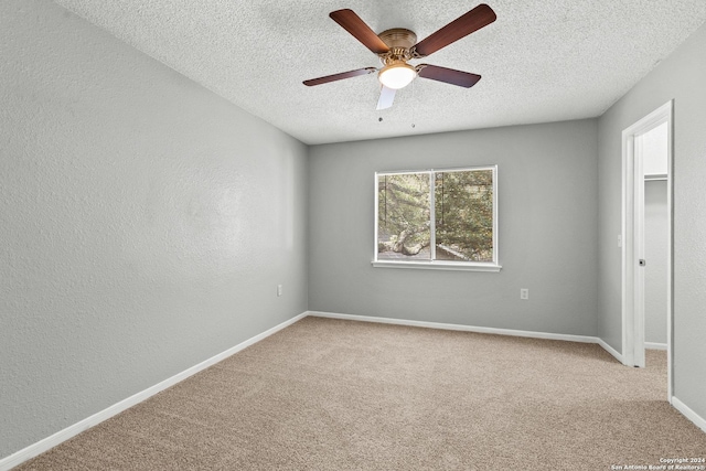 unfurnished bedroom featuring a textured wall, a ceiling fan, light carpet, a textured ceiling, and baseboards