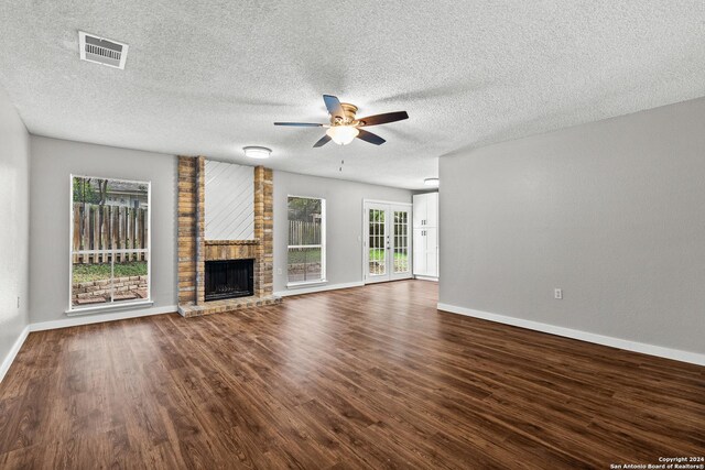 unfurnished living room featuring dark wood-style floors, a fireplace, visible vents, and plenty of natural light